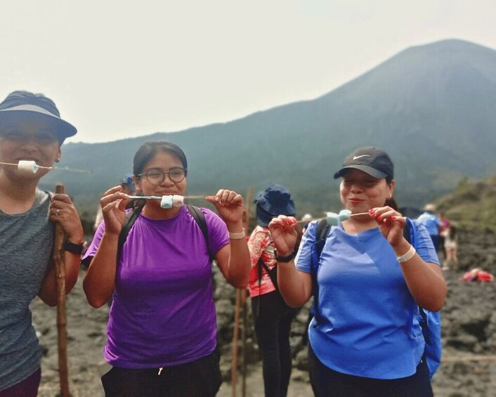 Three people with sticks, possibly for roasting marshmallows, in a mountainous area. 3