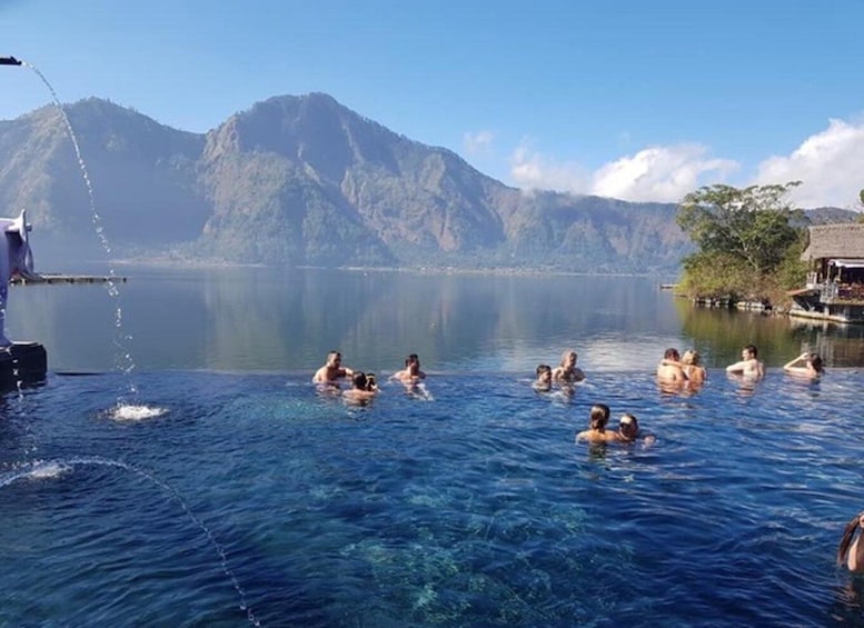 People swimming in a clear lake with mountains in the background. 2