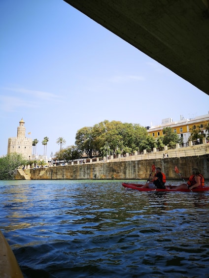 A river with kayakers, a bridge, and a historic tower. 1