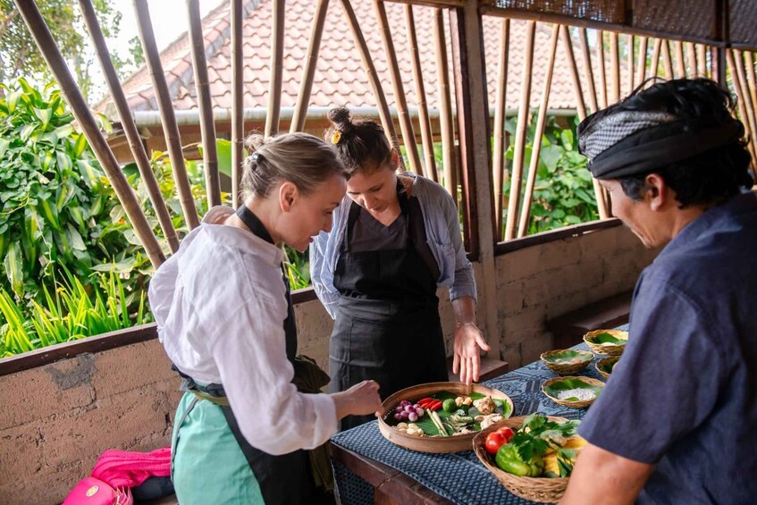 A group of people around a table with various food items and baskets. 1