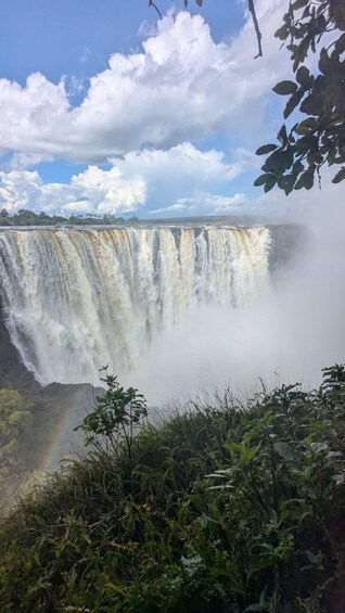 A waterfall cascading over a cliff, surrounded by lush greenery and a clear sky. 2