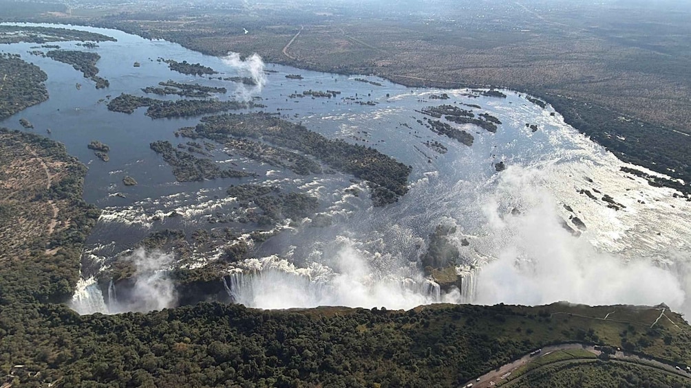 A large waterfall cascading over a cliff surrounded by dense forest and a river. 3