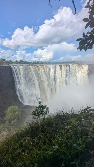 A large waterfall cascading down a cliff surrounded by lush greenery. 4