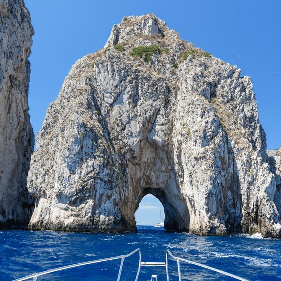 A rocky arch formation in the sea with a boat in the foreground. 3