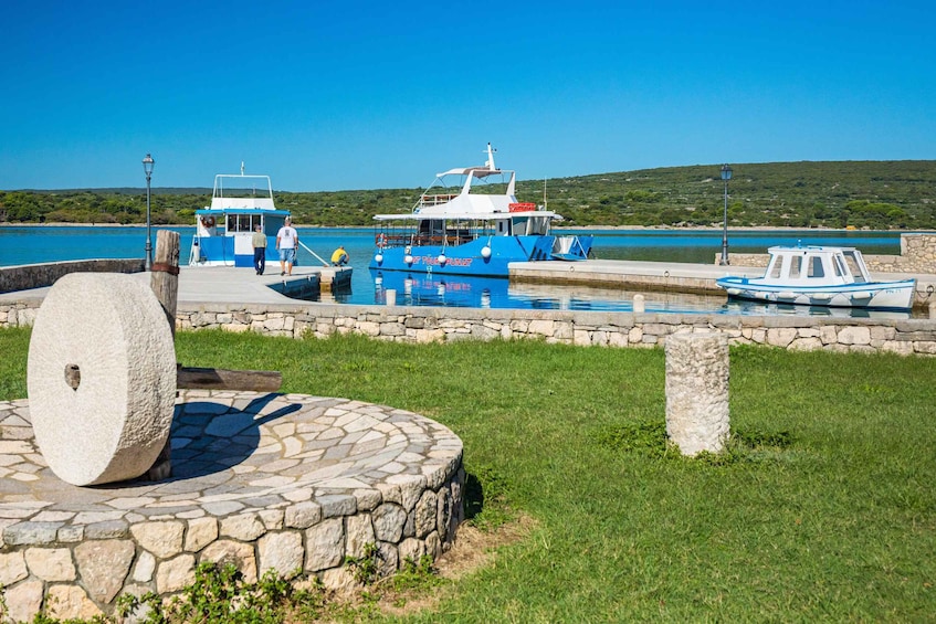 A harbor with boats, a stone fountain, and a grassy area. 2