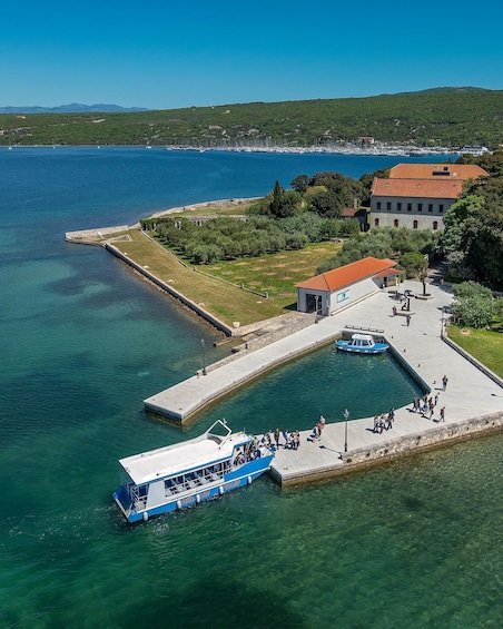 A coastal town with a clear blue sea, a docked boat, and a historic building. 5