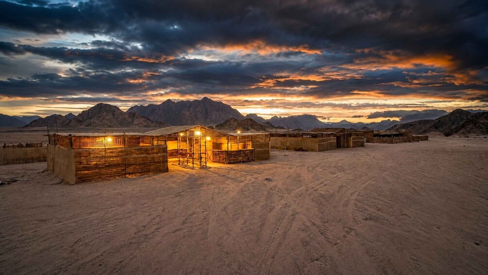 A desert landscape with wooden structures and mountains in the background. 5