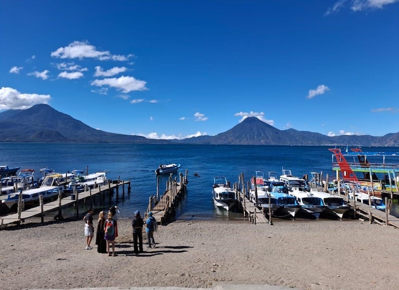 A marina with boats docked, a dock extending into the water, and a mountain in the background. 1