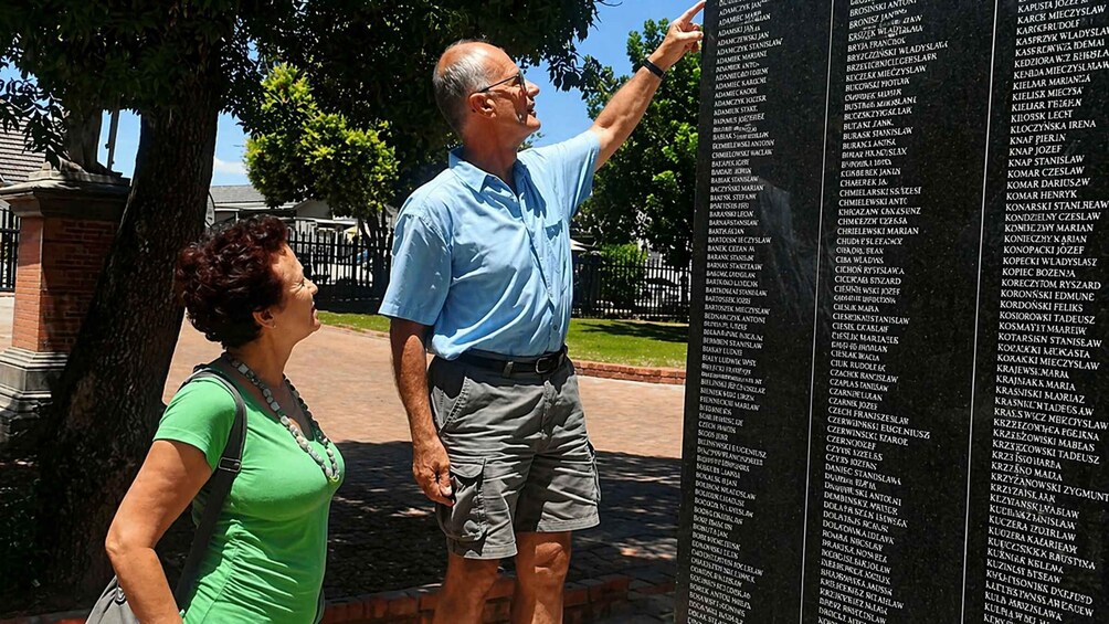 Two people examining a memorial plaque outdoors. 2