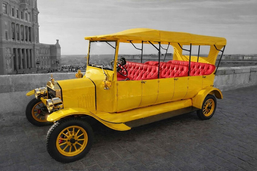 A yellow vintage car with red upholstery parked on a paved area. 5