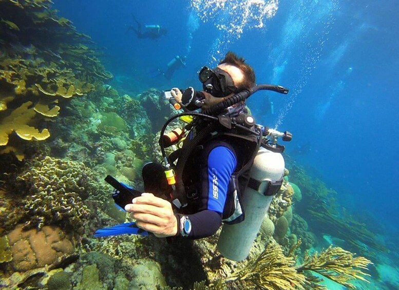 A scuba diver with a camera, surrounded by underwater coral and marine life. 1