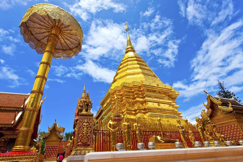 A golden stupa with intricate designs and a large umbrella structure in front. 1
