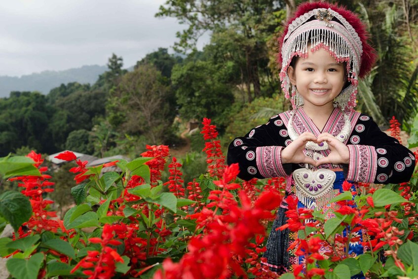 A person in traditional attire surrounded by red flowers. 4