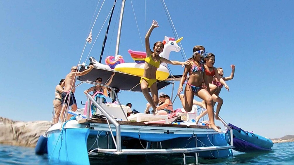 A group of people on a boat with a unicorn float and a rainbow float. 1