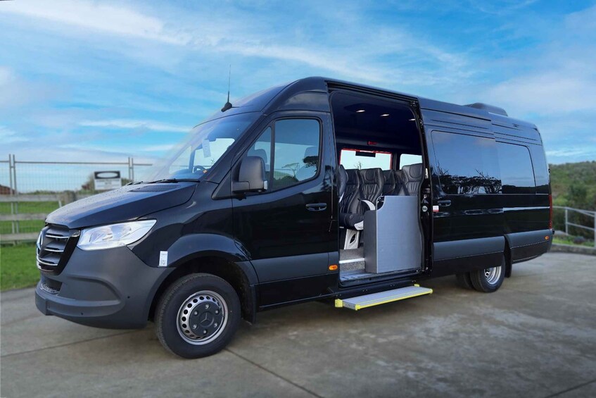 A black van with an open side door, parked on a concrete surface. 2