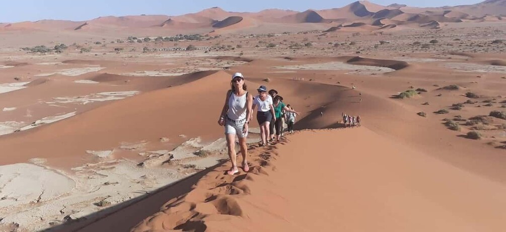 A group of people walking on a sand dune in a desert landscape. 4