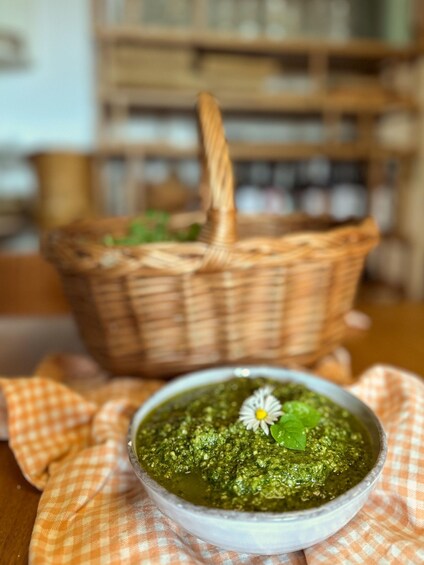 A bowl of green sauce with a flower on top, placed on a checkered cloth. 5