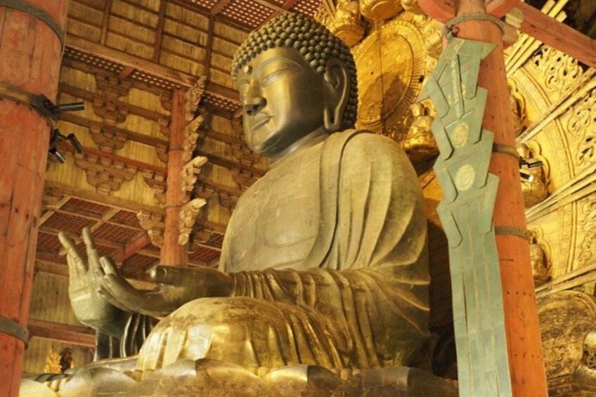 A large seated Buddha statue in a temple with intricate wooden architecture and golden decorations. 3