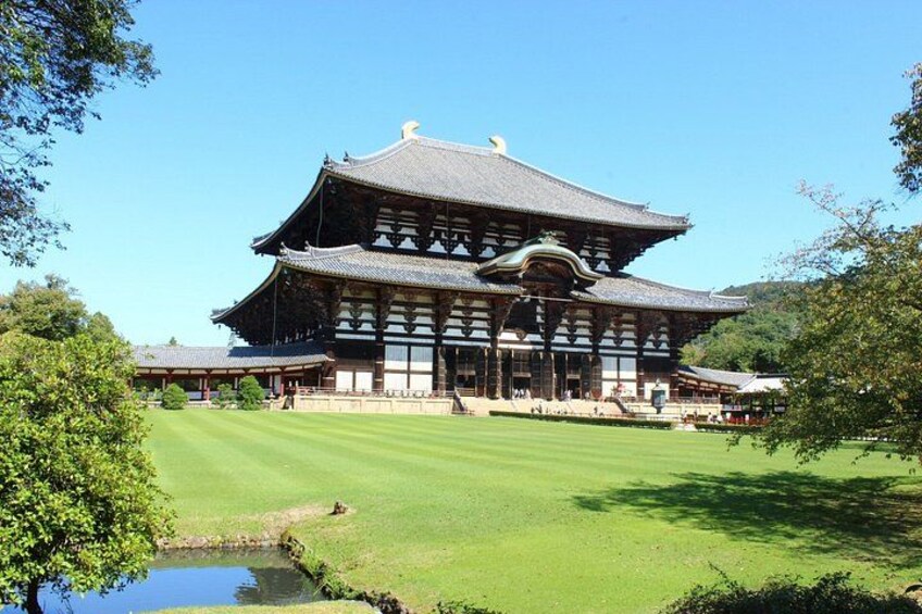 A traditional Japanese building with a large, ornate roof, surrounded by a well-maintained lawn and a small pond. 4