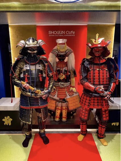 Three samurai in traditional armor at the Shogun Cafe, with a red backdrop and Japanese cultural symbols. 2