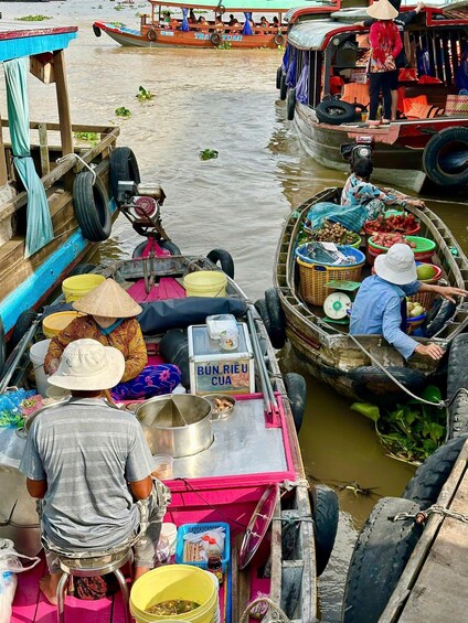 A floating market with boats carrying goods, people, and a sign reading 'BUN RIEU CUA'. 4