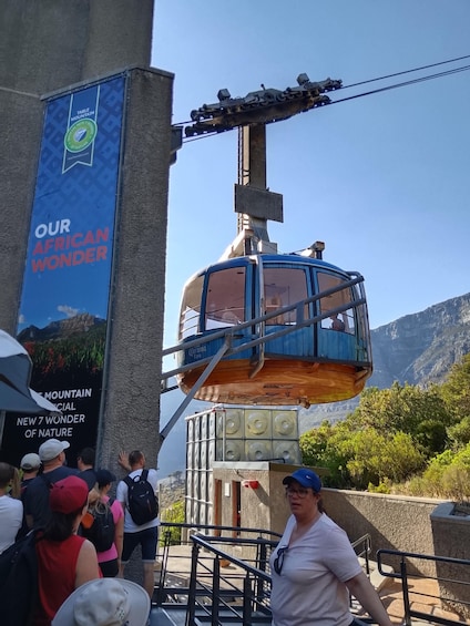 A cable car system with passengers, a mountain backdrop, and a banner advertising 'OUR AFRICAN WONDER.' 1