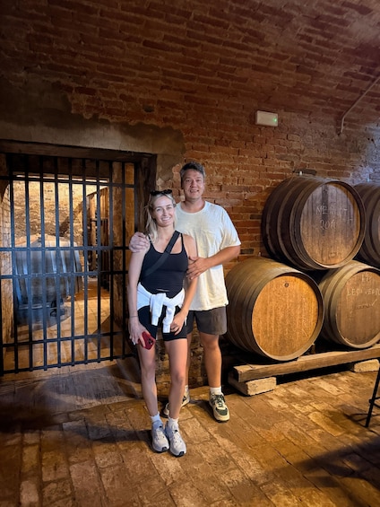 Dos personas de pie en una bodega con barriles de madera. 5