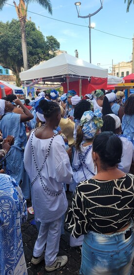 A group of people gathered outdoors, some wearing traditional attire with blue and white patterns. 3