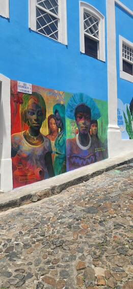 A colorful mural on a building with blue and white walls, depicting people in traditional attire. 5