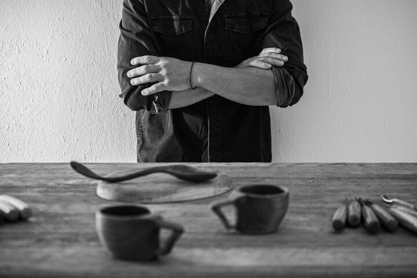 A person standing with arms crossed in front of a table with kitchen utensils and cups. 2