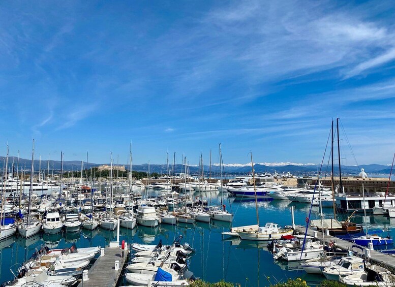 A marina filled with various boats, a clear blue sky, and distant mountains. 1