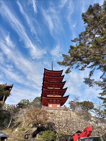 A traditional multi-tiered pagoda with a stone wall and trees in the foreground. 5
