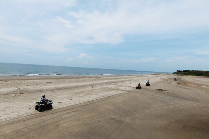 A beach with four off-road vehicles on the sand. 1