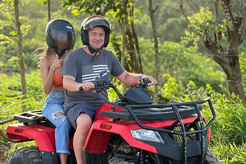 A person riding a red ATV in a forested area. 2