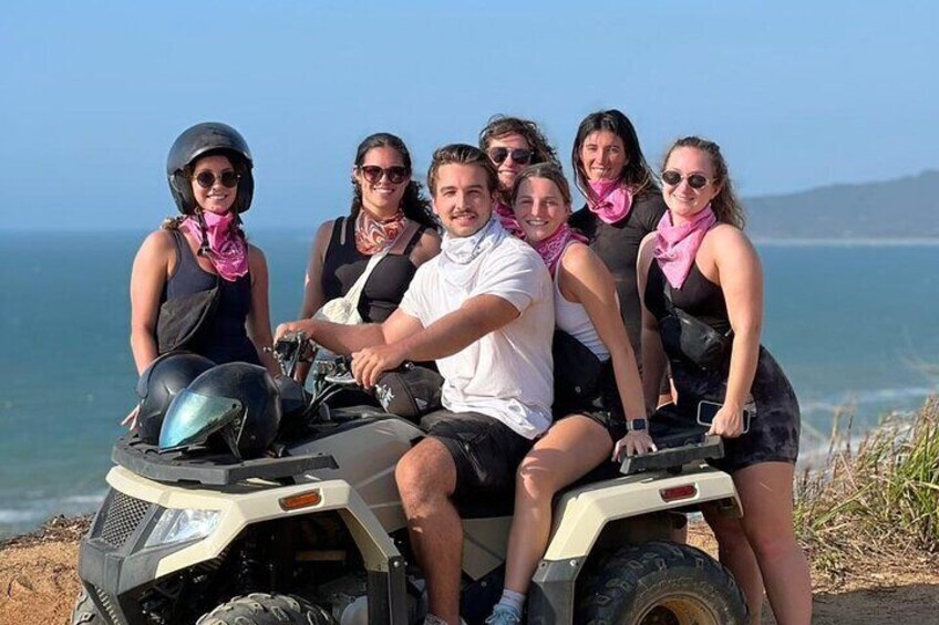 A group of people on an ATV near a coastal area. 2