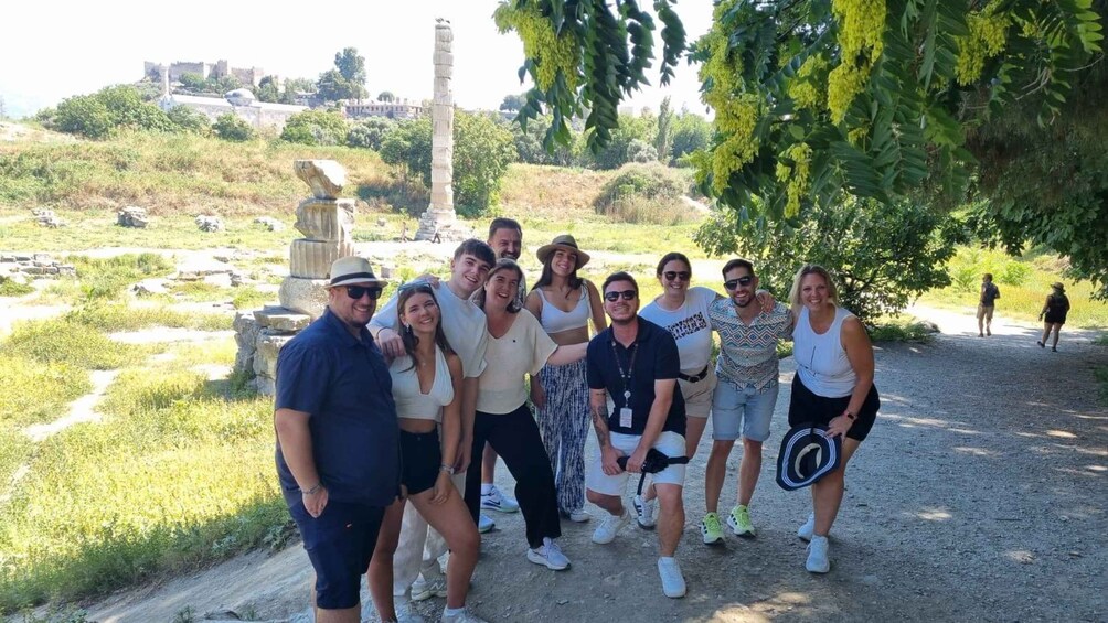 A group of people posing in a park with ruins and greenery. 1