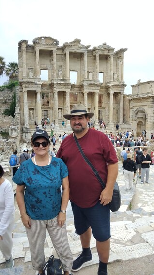 A man and a woman standing in front of an ancient ruin with columns and arches. 5