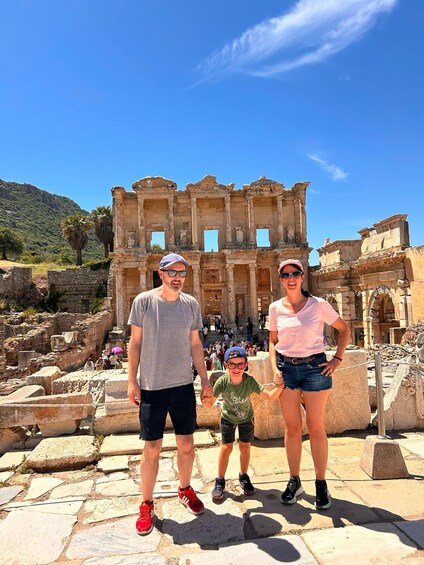 A family standing in front of ancient ruins with columns and a clear blue sky. 3