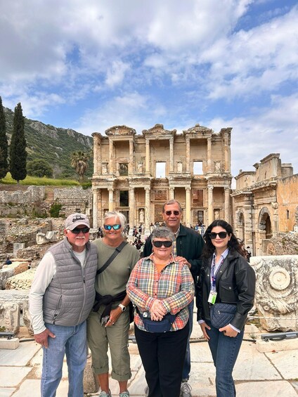 A group of people standing in front of ancient ruins with columns and a mountain in the background. 2