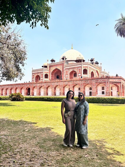 Two people standing in front of a large, ornate building with domes and arches. 5