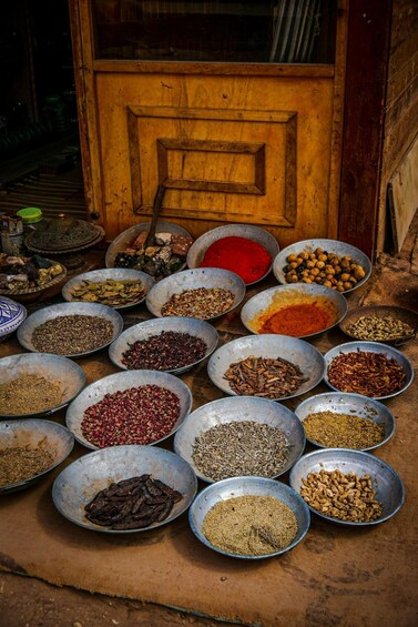 A variety of spices displayed in metal bowls outside a wooden door. 1