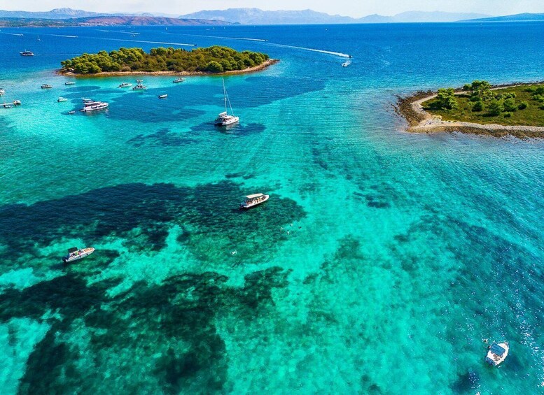 A turquoise sea with boats and a small island with trees. 1