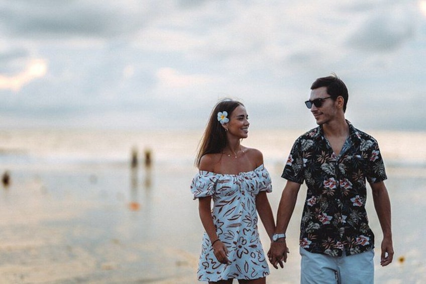 A couple walking on a beach with the ocean in the background. 1