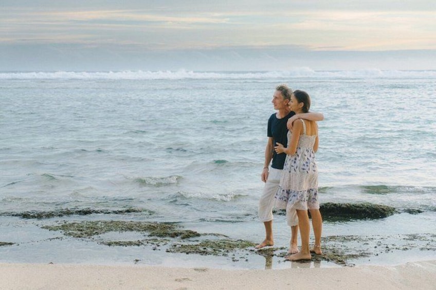 A couple standing on a beach with the ocean in the background. 3