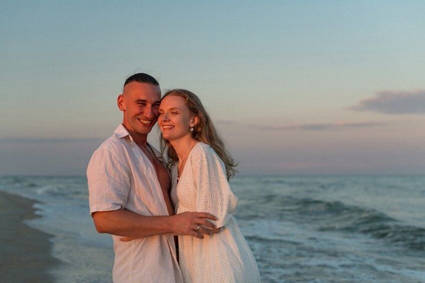 A couple embracing on a beach with the ocean in the background. 4