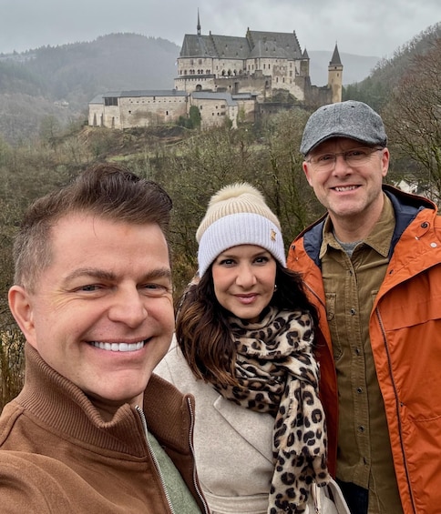 Three people in front of a historic castle on a hill. 2