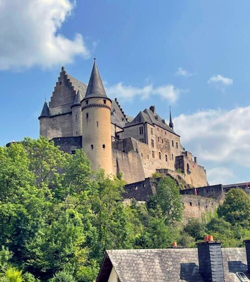 A medieval castle with multiple towers and a prominent central tower, surrounded by lush greenery. 5