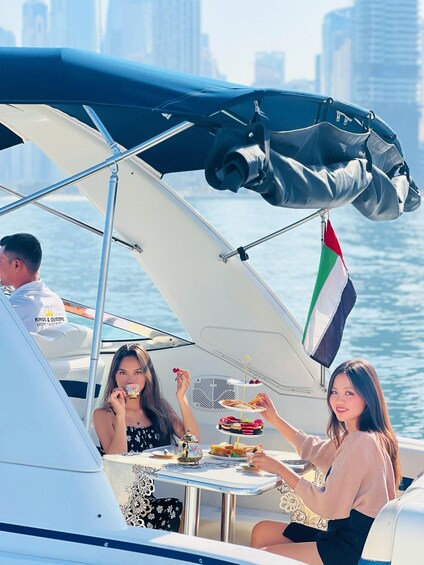 A boat with a UAE flag, people dining, and a city skyline in the background. 4