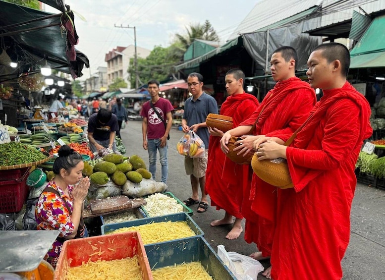 Monks in red robes at a market stall with vegetables and fruits. 2