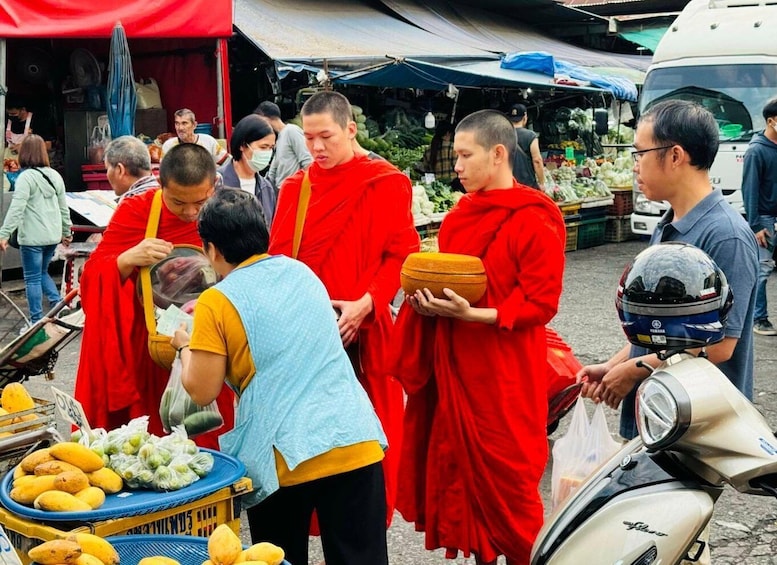 Monks in red robes at a market, interacting with a vendor. 5
